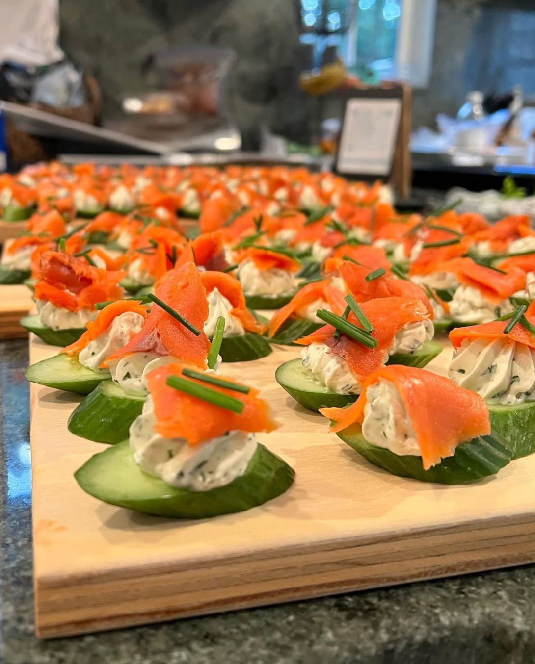 Smoked salmon and cucumber canapés in rows.
