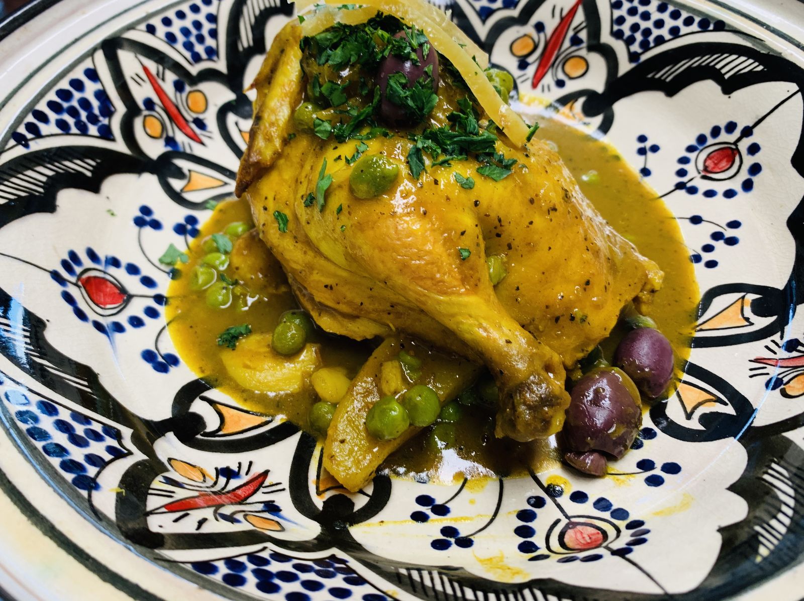 Chicken with green olives and preserved lemon in a golden sauce, on hand-painted Moroccan pottery.