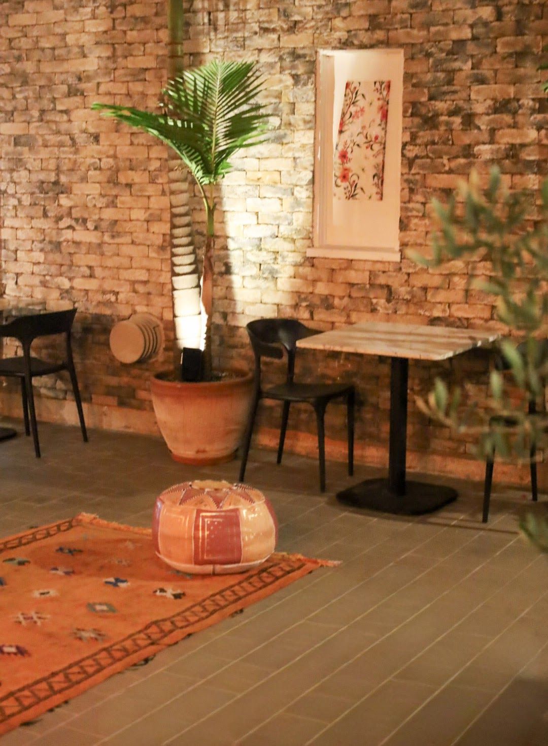 A corner of the courtyard: exposed brick, a palm in a terracotta pot, a Berber rug and a leather pouf.