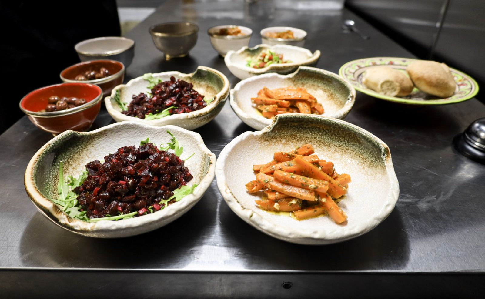 A spread of small Moroccan salads in ceramic bowls: beets, spiced carrots, eggplant and tomato with cucumber.