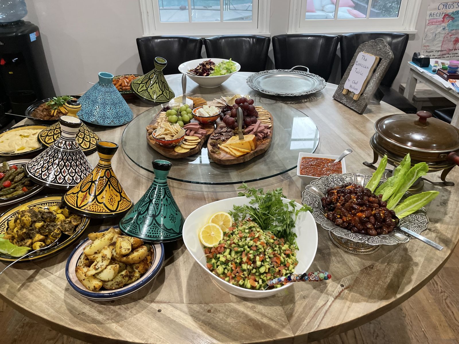 A round table set with painted tagines, salads and mezze for a corporate lunch.