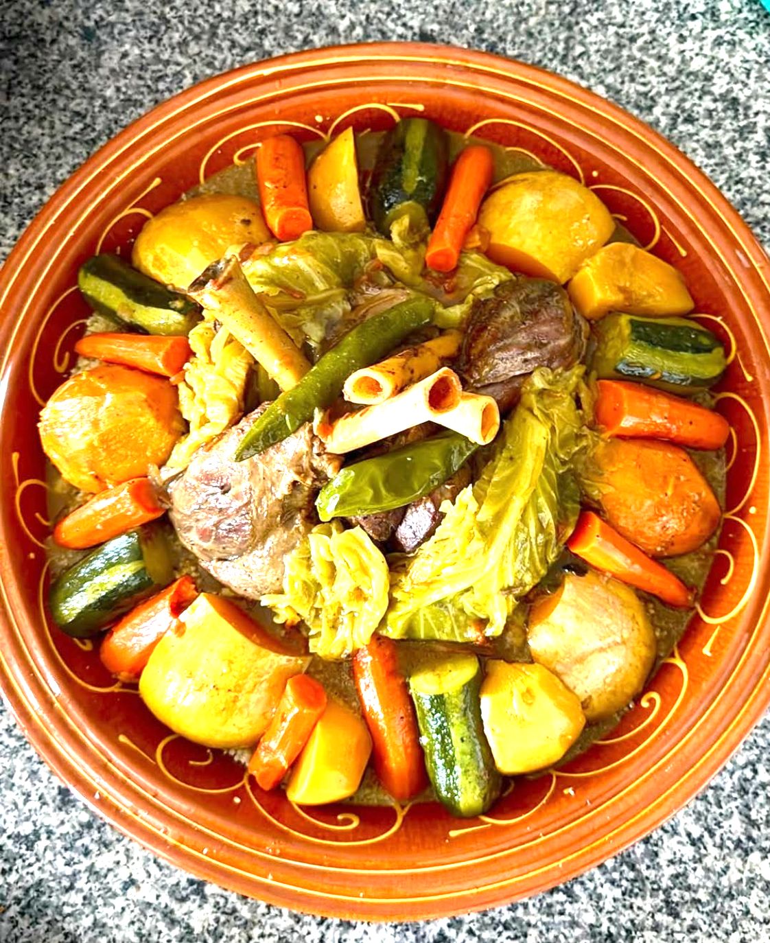 Seven-vegetable couscous with lamb in a painted clay dish.